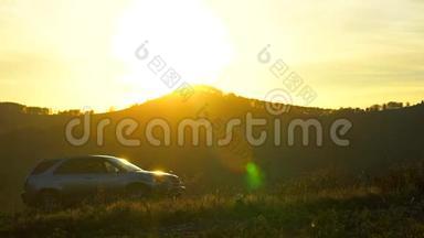 日落时分在戈里崇山峻岭中行驶的汽车剪影，太阳镜头耀斑，户外。 乡村公路。 山岭山山岭山